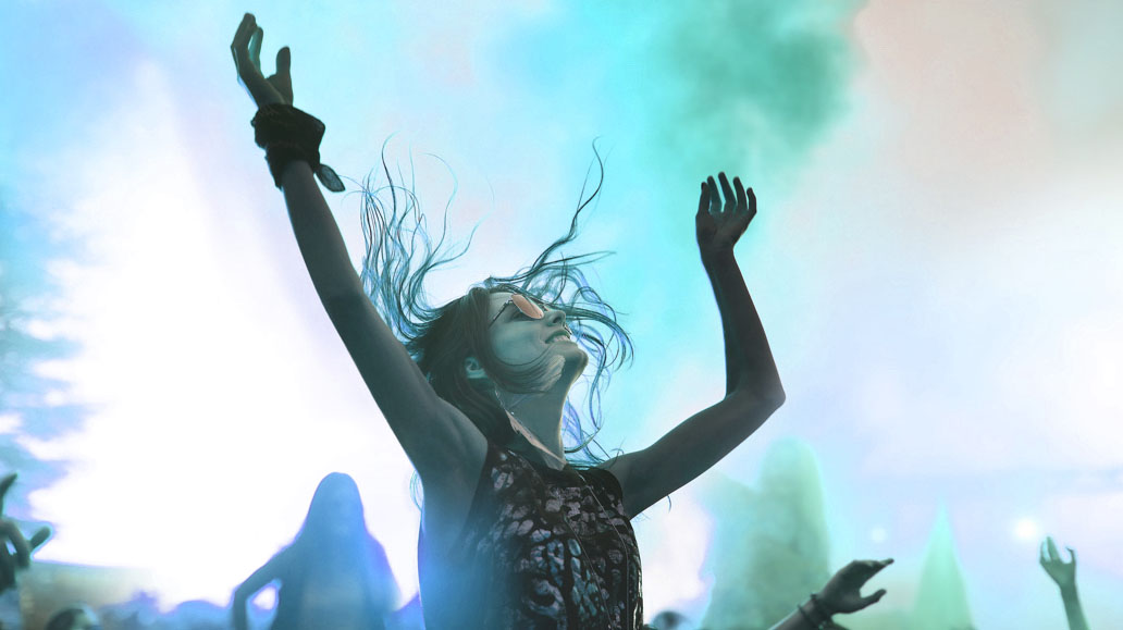 woman with her hands up against the backdrop of an outdoor concert