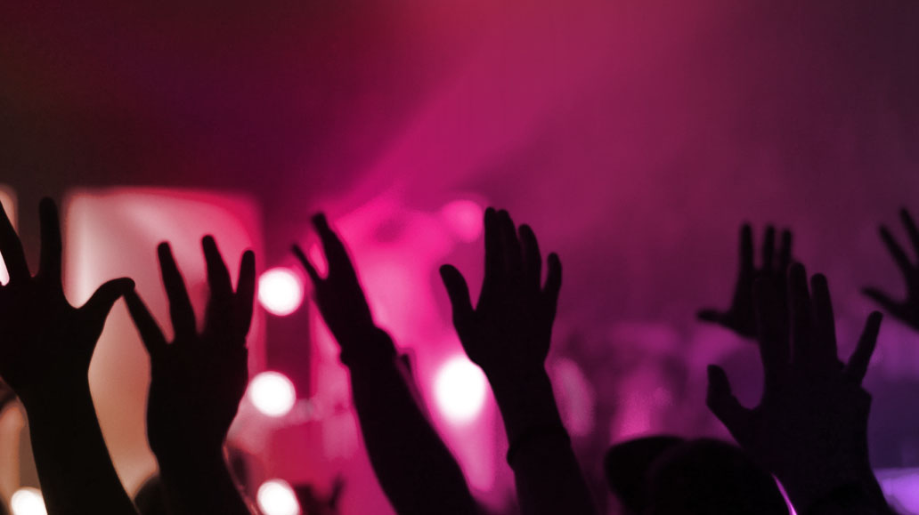 group of people with their hands up in the air in a concert