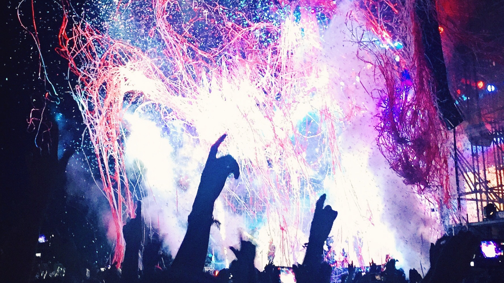 people standing in front of a large display of fireworks at a concert